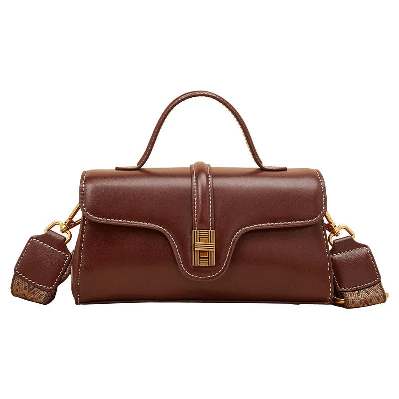 Brown Cambridge-style crossbody messenger bag with clamshell opening and lock detail on a table.