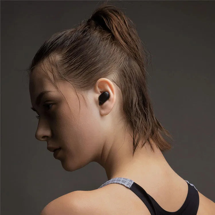 Redmi AirDots black true wireless earbuds and charging case on a table.