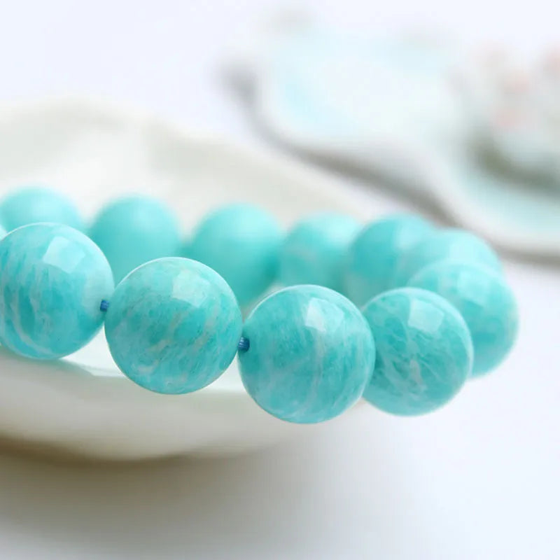 A single green amazonite bead bracelet on an elastic cord, shown in a natural setting.