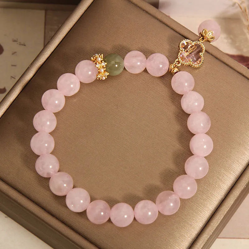 Pink crystal four-leaf clover pendant bracelet for women with rhinestones on alloy band.