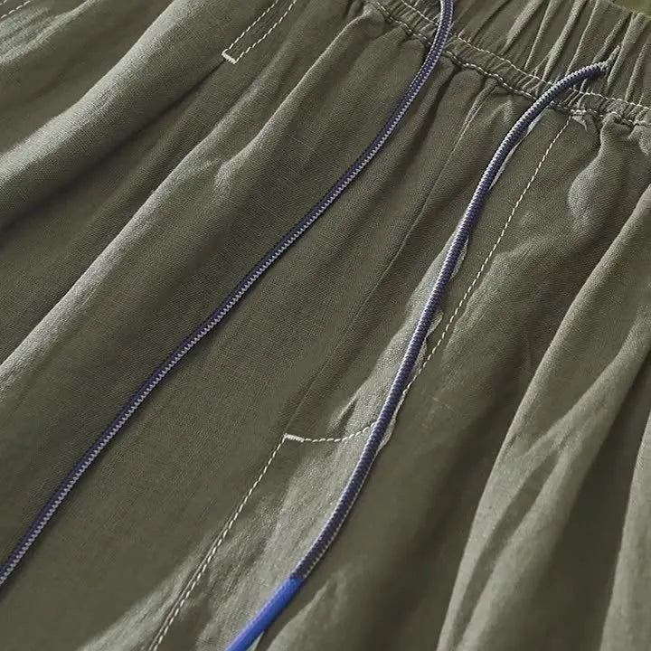 Men's linen shorts in straight drooping style with drawstring waist, shown in green and black colour options