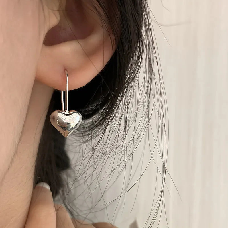 Silver-coloured heart-shaped earrings with three-dimensional glossy design and Korean-style aesthetic
