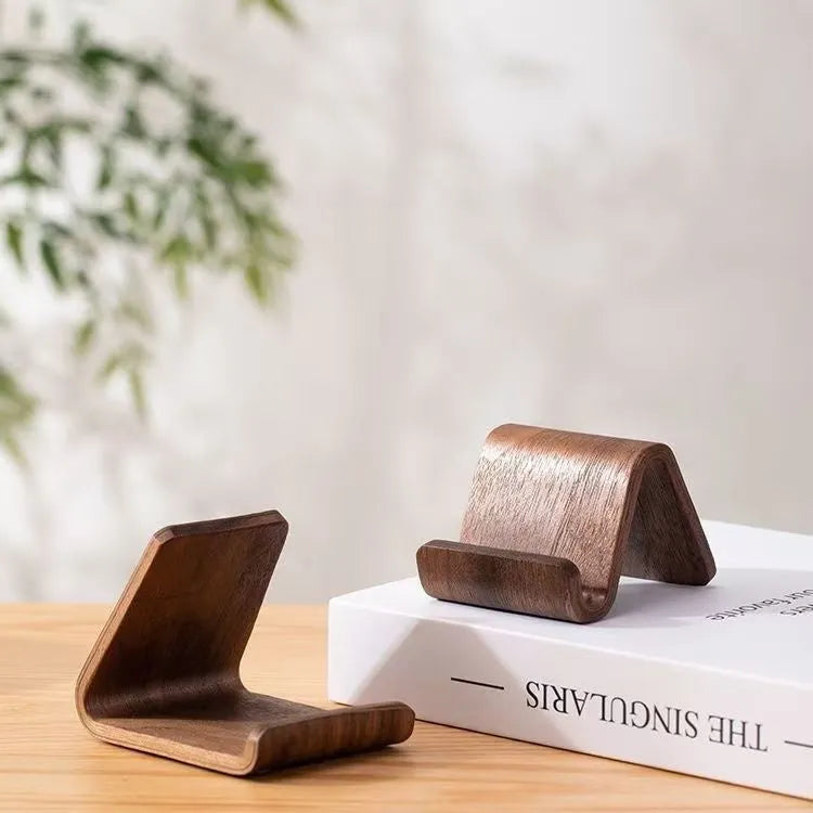 Walnut wood mobile phone bracket holding a smartphone on a wooden desk