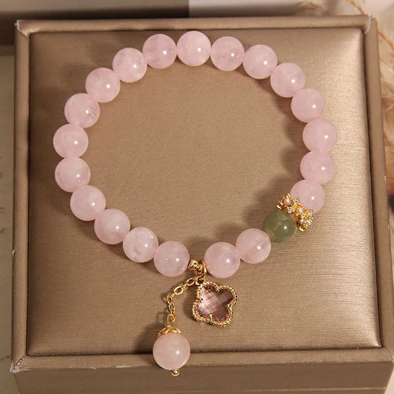 Pink crystal four-leaf clover pendant bracelet for women with rhinestones on alloy band.