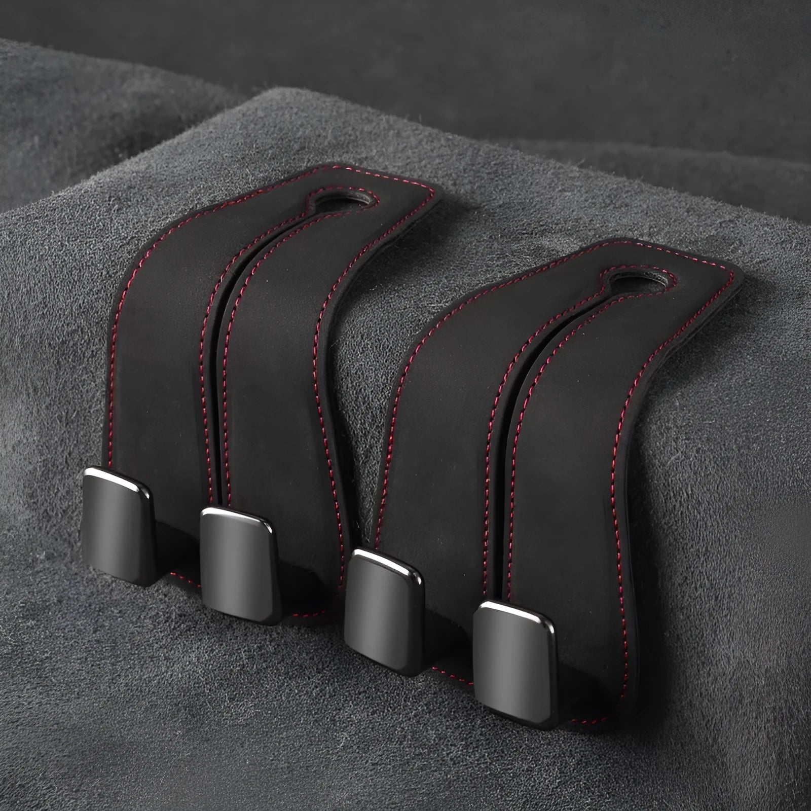 Black suede car seat hook attached to a headrest post, holding a shopping bag.