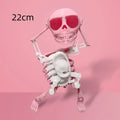 3D printed dancing skeleton gravity toy in pink and white, 22cm tall, on a desk