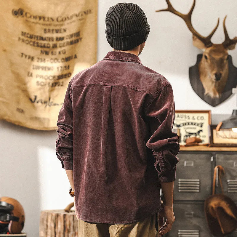 A man wearing a loose-fit black corduroy shirt jacket with long sleeves.