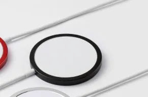 Silver metal Magsafe wireless charger for iPhone on a wooden surface.