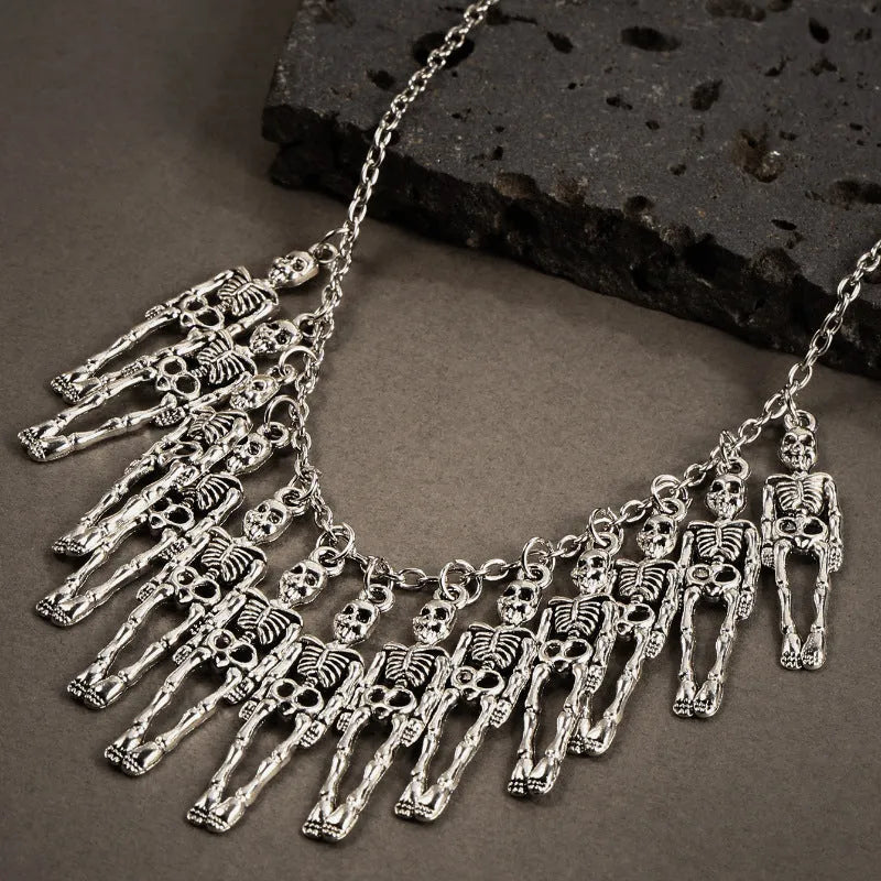 Silver alloy skull and ghost claw necklace with matching earrings set on a dark background.