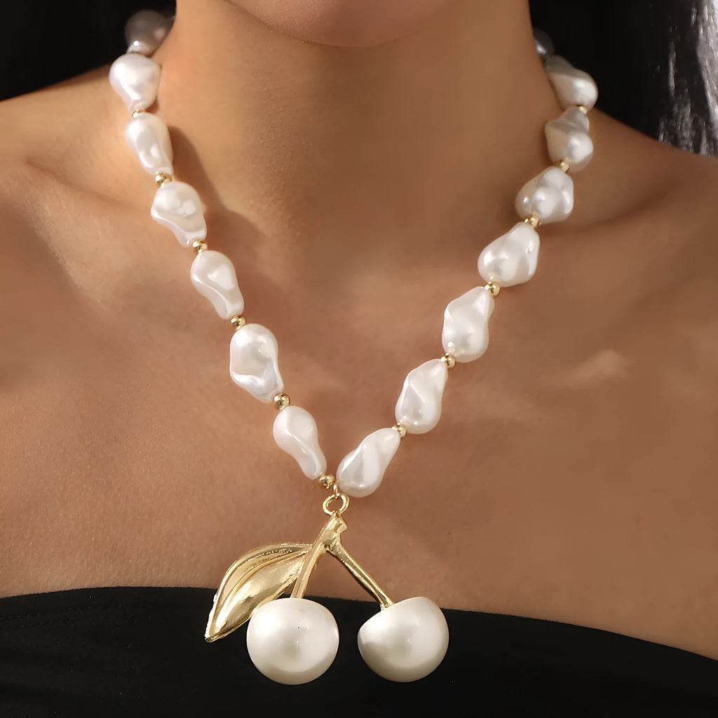 Gold coloured cherry fruit pendant necklace with imitation pearls on an adjustable chain.