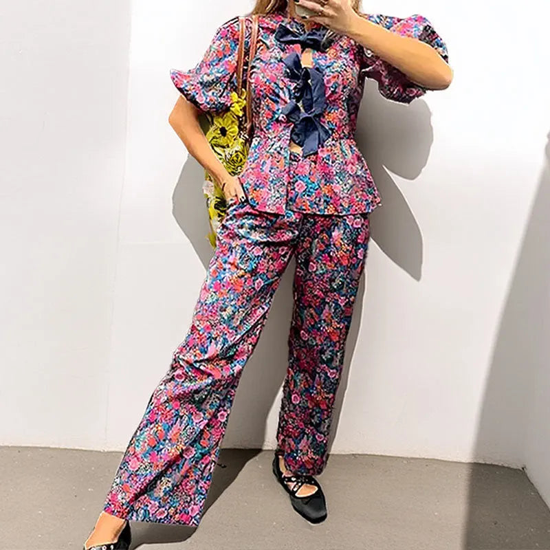 Women's floral printed trousers suit with tie-neck puff sleeve top and matching trousers in polyester fabric