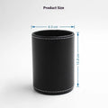 Round black leather pen container on desk holding writing instruments