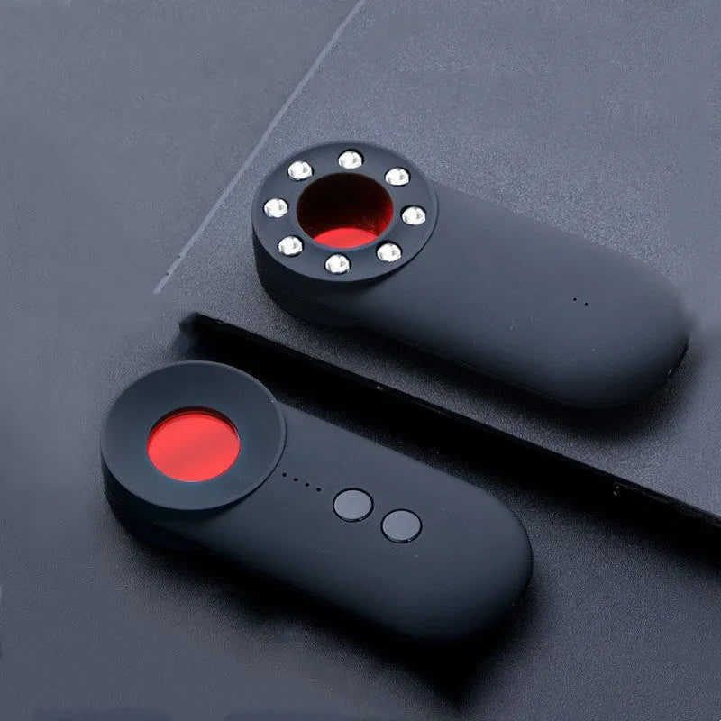 Black portable GPS and hidden camera detector with USB charging cable on a grey background.