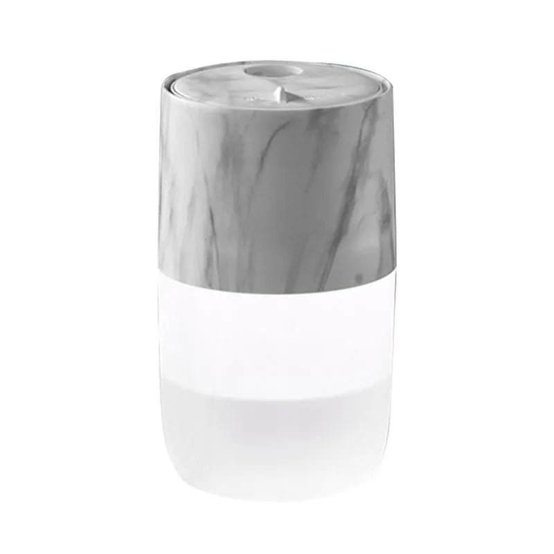 Mini portable jellyfish-shaped ultrasonic humidifier in black, with USB cable and essential oil bottle on a desktop