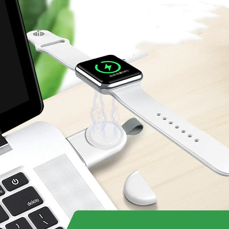 Portable white wireless charging dock for Apple Watch on a desk next to a laptop.