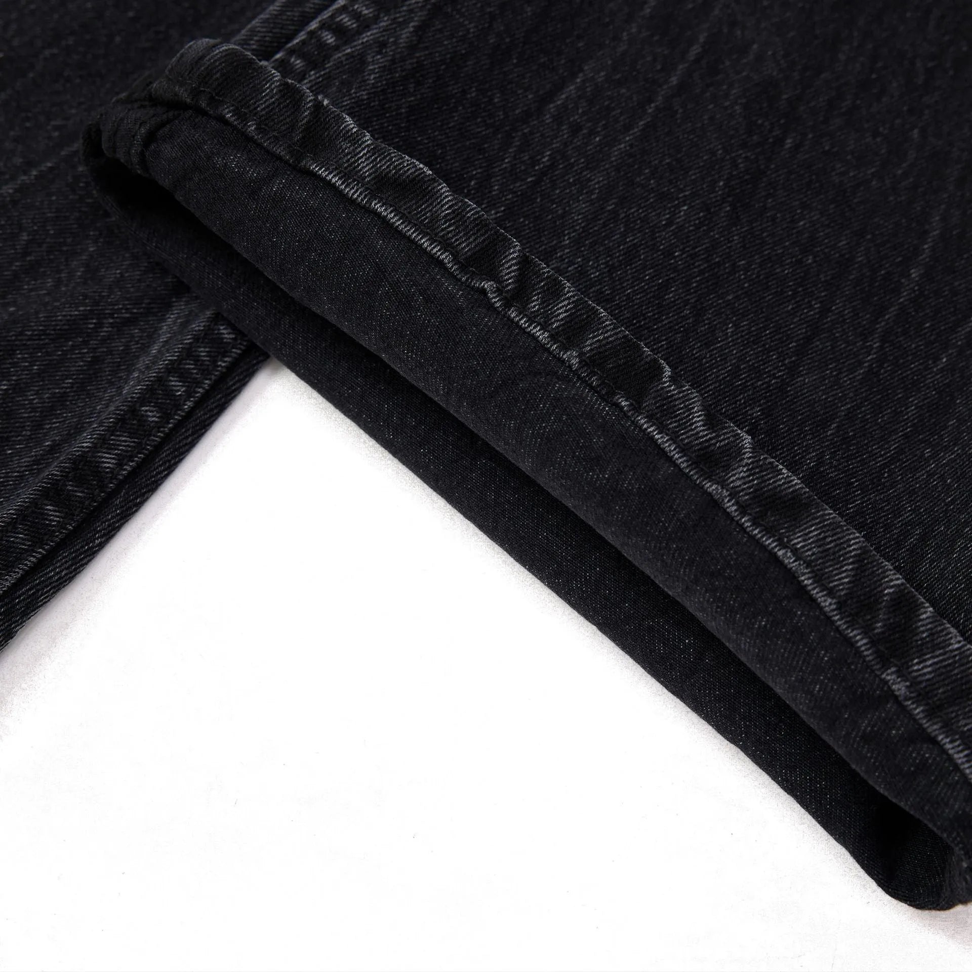 Black men's straight-leg jeans showing a cracked, washed denim finish on a plain background.