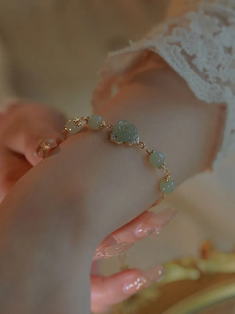 Close-up of a women's Hetian Jade bracelet with rose design and 14K gold gilding.