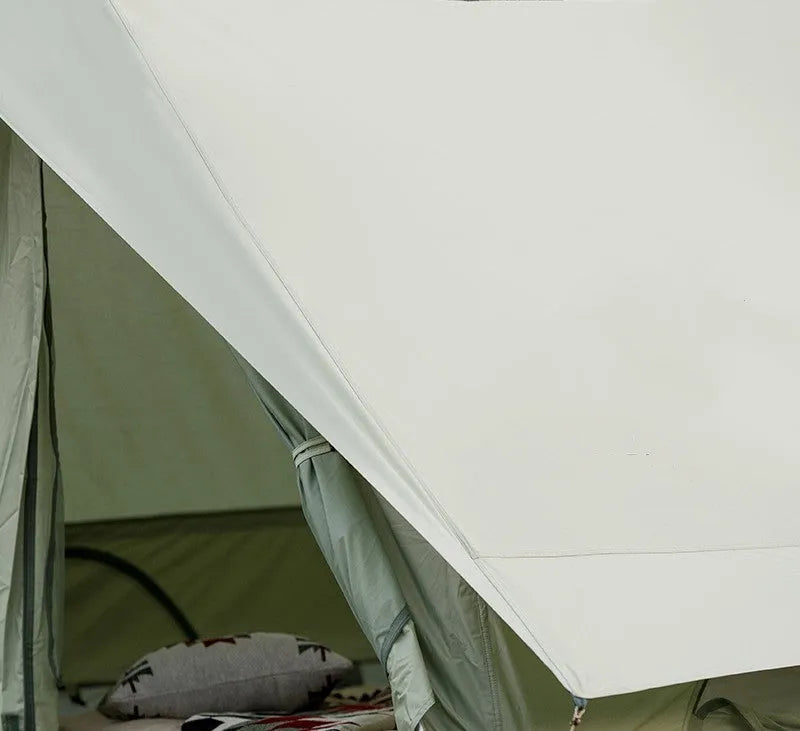 Large light luxury family camping tent in ivory white with cotton-polyester outer and aluminium poles set up outdoors