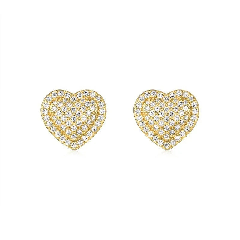 A pair of golden heart-shaped stud earrings with moissanite stones on a grey background.