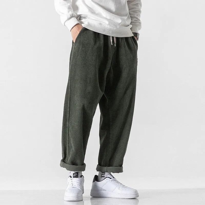 Men's loose straight-leg corduroy sports trousers in army green, laid flat to show fit and texture.