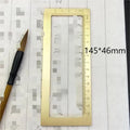 Solid brass calligraphy paper weight with engraved design on a wooden desk.