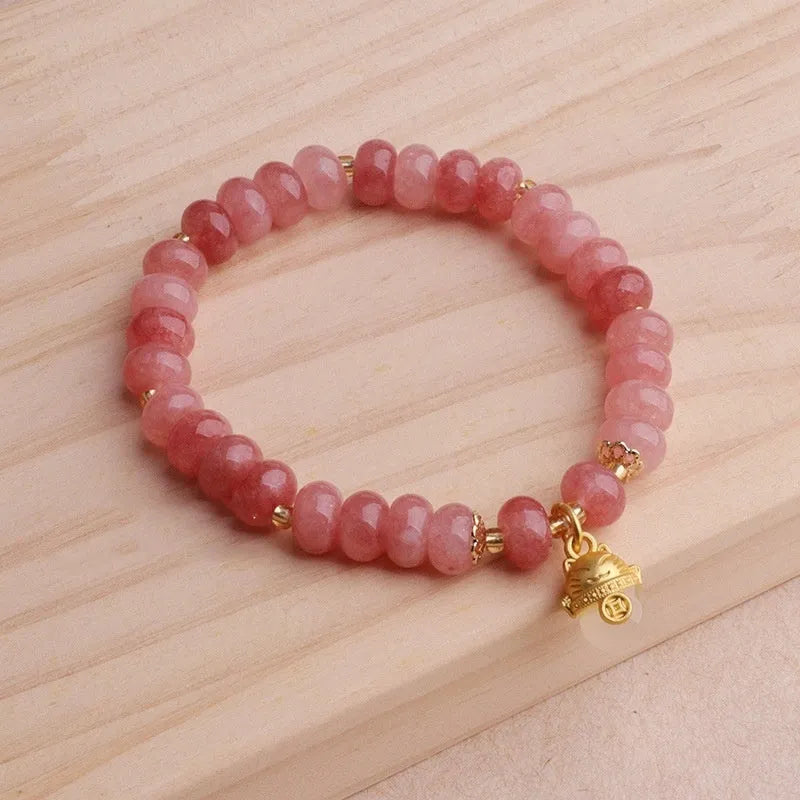 Women's lucky cat bracelet made from strung strawberry quartz or grey jade stones with zodiac charms.