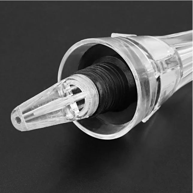 Clear acrylic wine aerator with stainless steel filter, shown next to a wine glass.