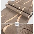Close-up of curve stripe pattern on textured velvet wallpaper in dark brown, showing 3D effect.