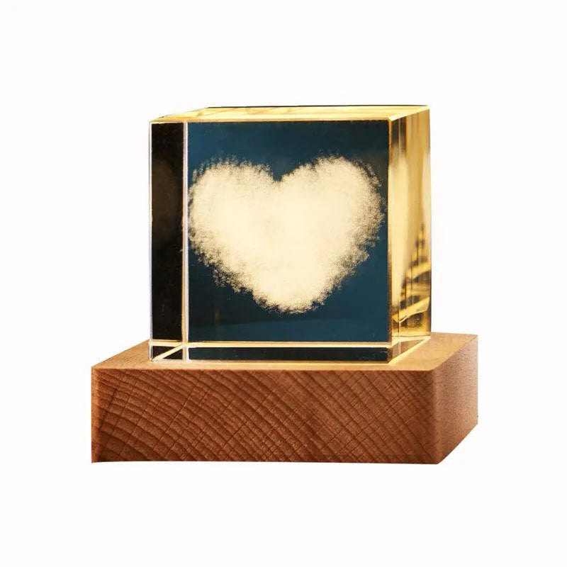 Transparent glass cube night lamp projecting a warm nebula light pattern on a desk.
