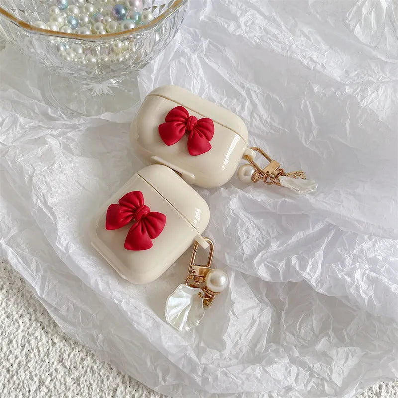 Beige AirPods case with red bow decoration, clamshell design for AirPods Pro and AirPods 3 models