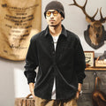 A man wearing a loose-fit black corduroy shirt jacket with long sleeves.