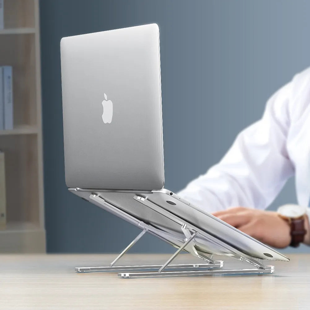 A folded aluminium laptop stand in rose gold next to an open silver laptop on a desk.