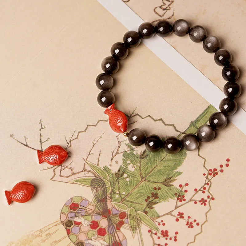 Natural obsidian round bead bracelet with red cinnabar fungus decorative elements.