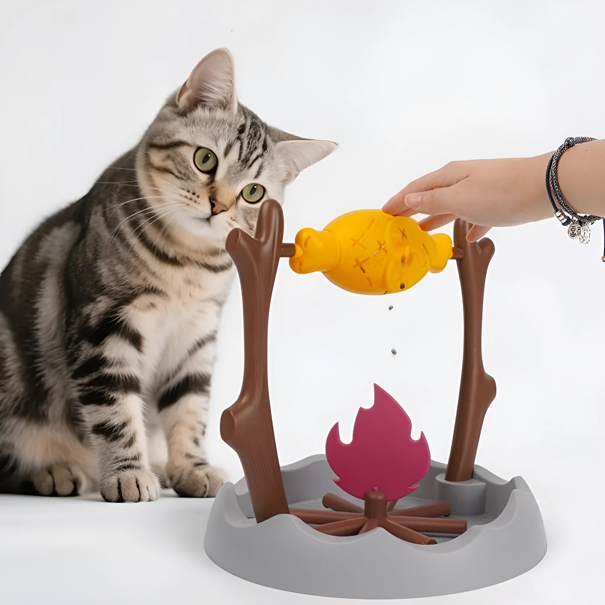 Barbecue-style plastic tumbling cat feeder toy for dispensing freeze-dried treats.