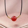 Hand-woven red agate bracelet and necklace set with bean-shaped beads on a textile background.