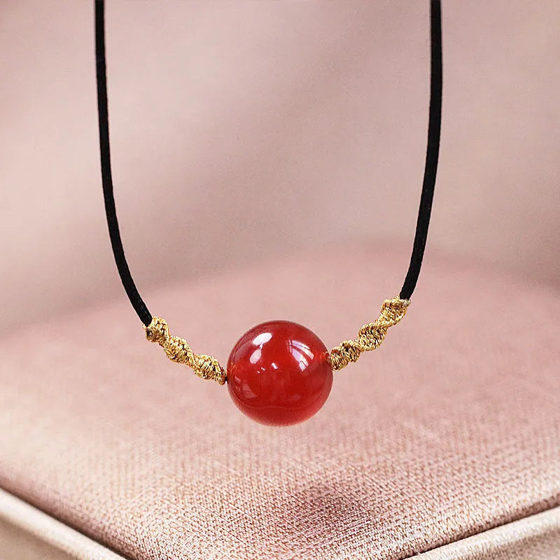 Hand-woven red agate bracelet and necklace set with bean-shaped beads on a textile background.
