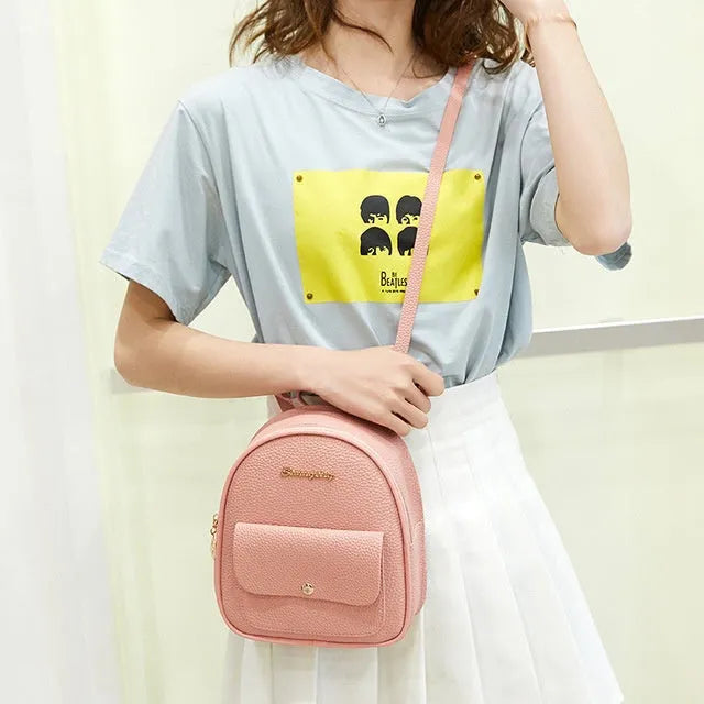 A compact black PU women's backpack purse with a zipper, shown as a small shoulder bag.