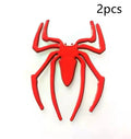 Three-dimensional metal spider bumper sticker in zinc alloy, shown in gold colour, measuring 7 by 5 cm.