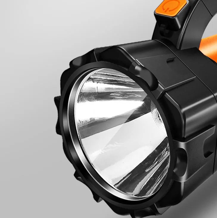 Orange portable LED work lamp with adjustable brightness, side lights, and removable battery on shoulder strap.