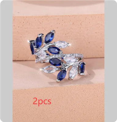Adjustable copper leaf-shaped ring with zircon stones in various colour options on a white background.