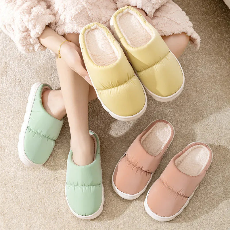 A pair of thick-soled house slippers with an artificial leather upper and plush lining, shown in a choice of colours.