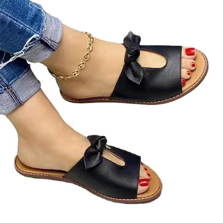 Ladies black sandals with fish mouth toe and a gold bow on the strap.