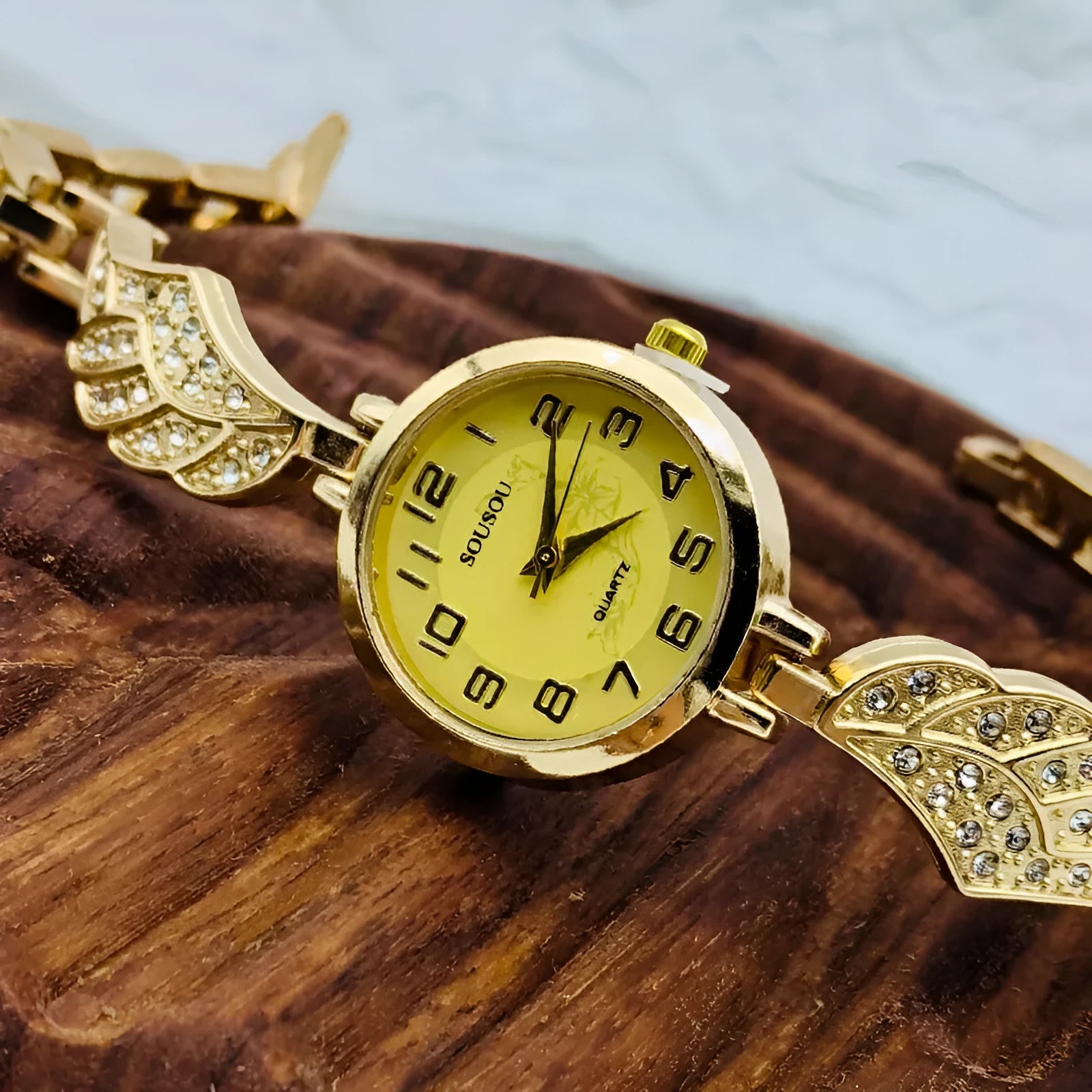 Stainless steel women's watch with round dial on wrist, showing gold colour surface and vachette clasp.