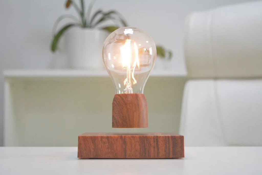 Magnetic levitation light bulb floating above wood-effect base with international plug adapters