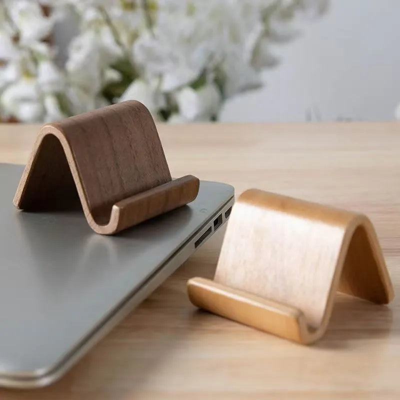 Walnut wood mobile phone bracket holding a smartphone on a wooden desk