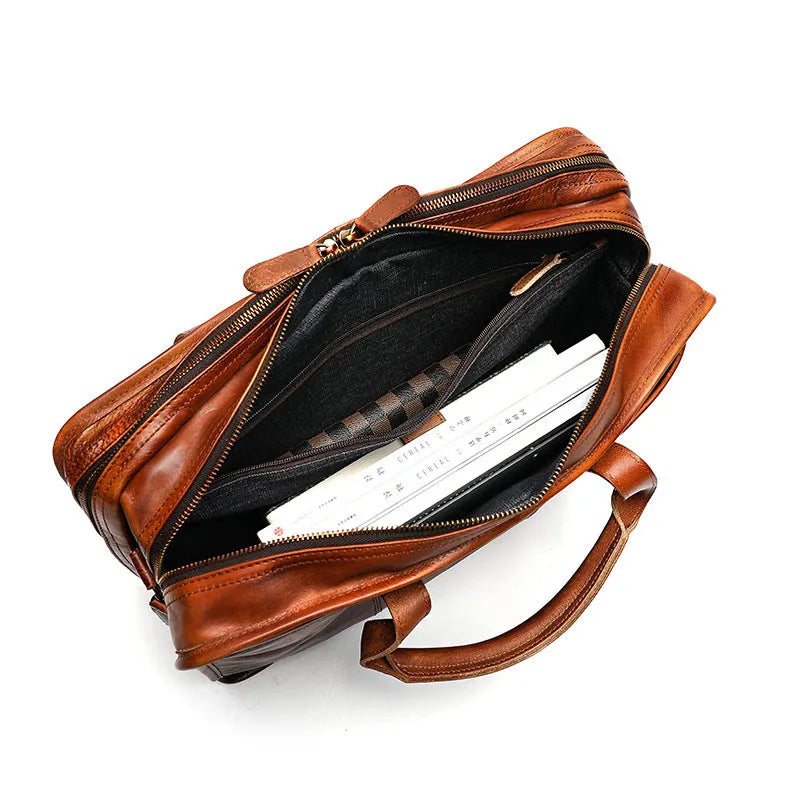 Brown vintage leather men's briefcase open to show internal laptop pocket and document organisers.