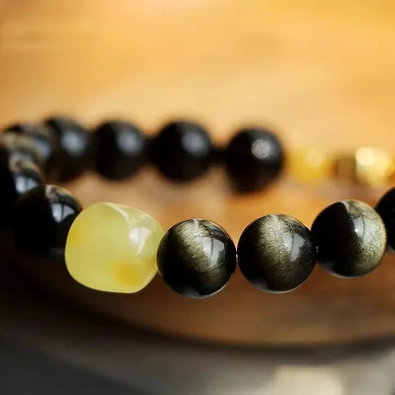 Handmade golden obsidian bracelet with 10mm geometric beads on a wrist, showing ethnic zodiac design.