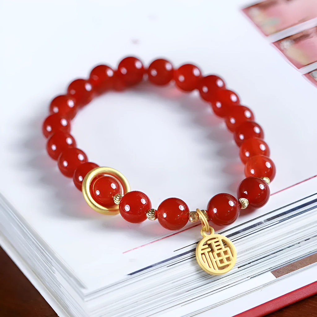 Close-up of a woven red agate bracelet showing bead detail and blessing card.