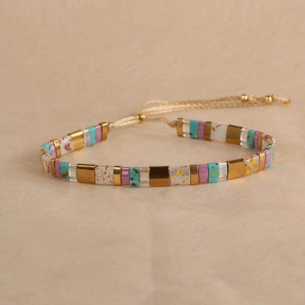 Geometric beaded bracelet with round elements in milky white, black, green, blue, or red.