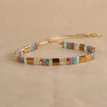 Geometric beaded bracelet with round elements in milky white, black, green, blue, or red.